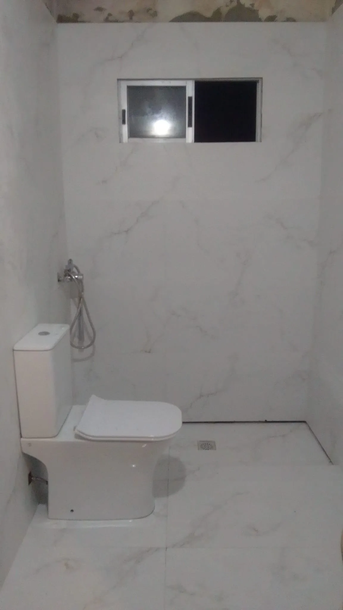 El mismo baño reformado, con porcelánico blanco y sanitario nuevo