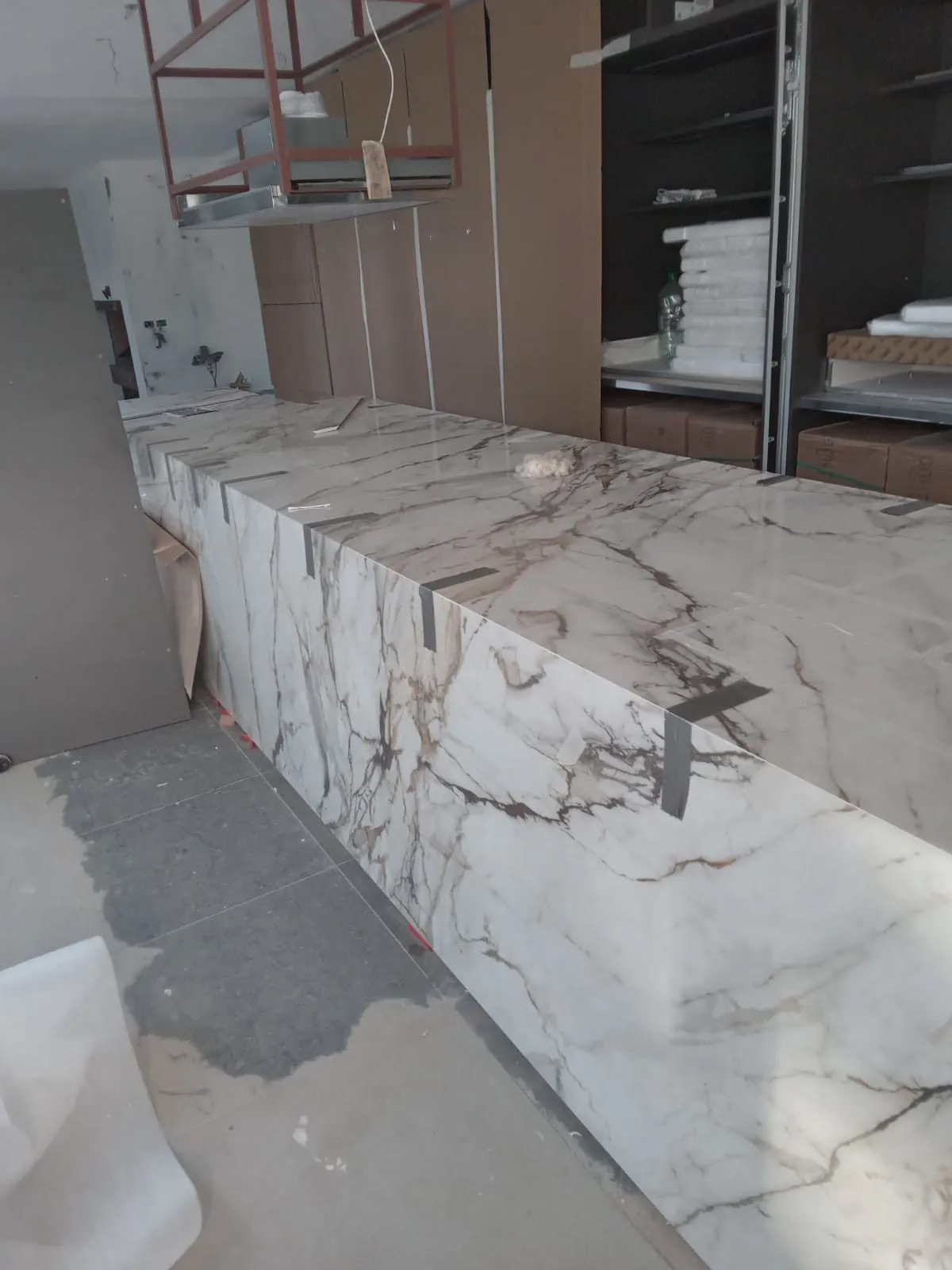 Isla de cocina revestida de porcelánico efecto mármol, durante el montaje