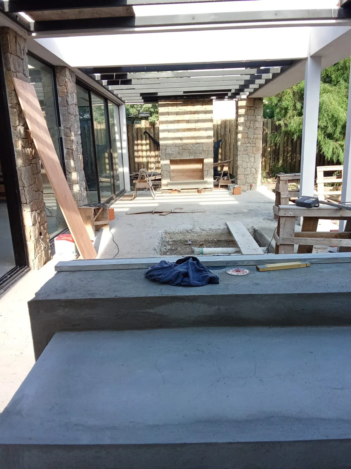 Patio en obra con bancada de hormigón y chimenea exterior al fondo